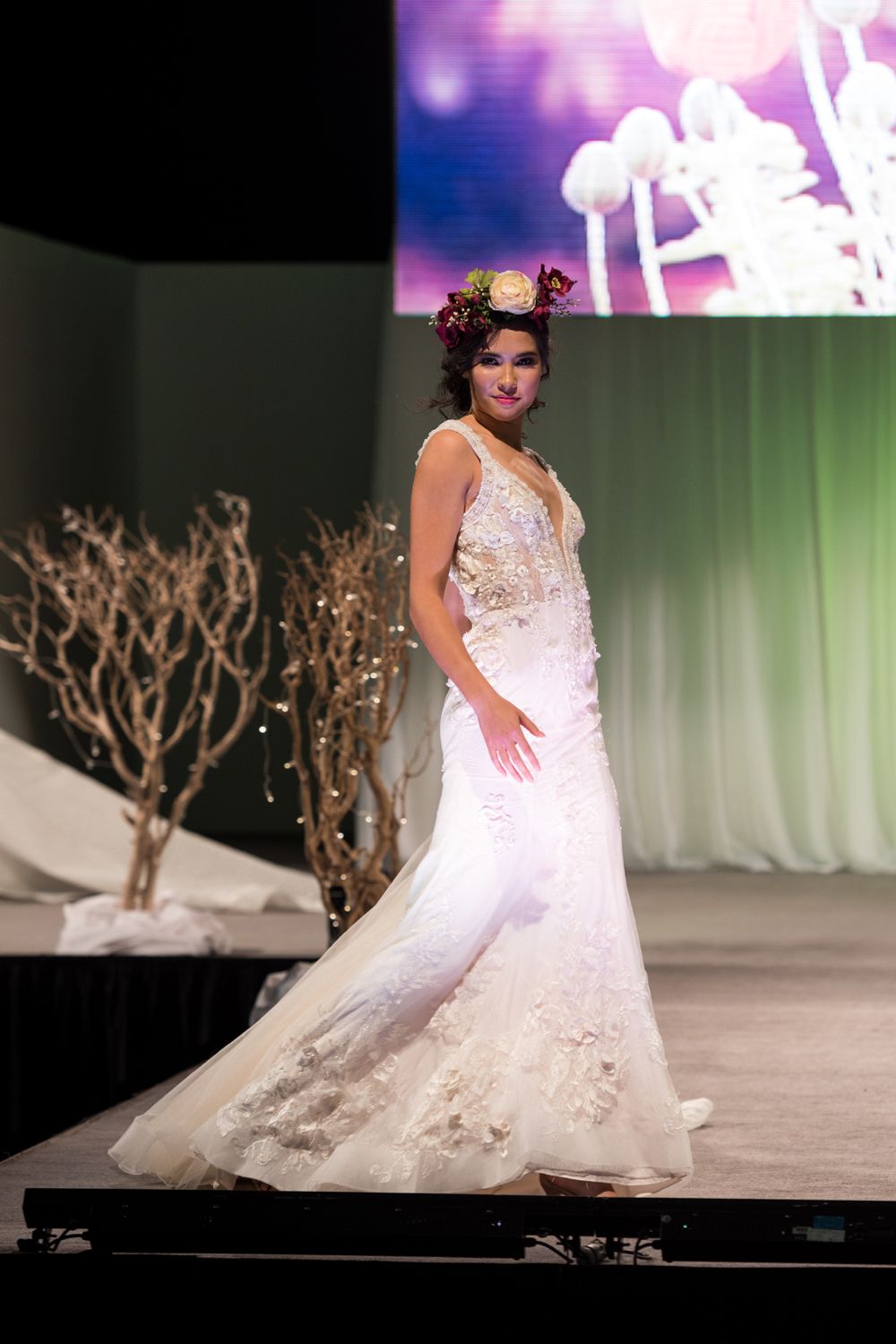 A woman in a wedding dress is walking down a runway.