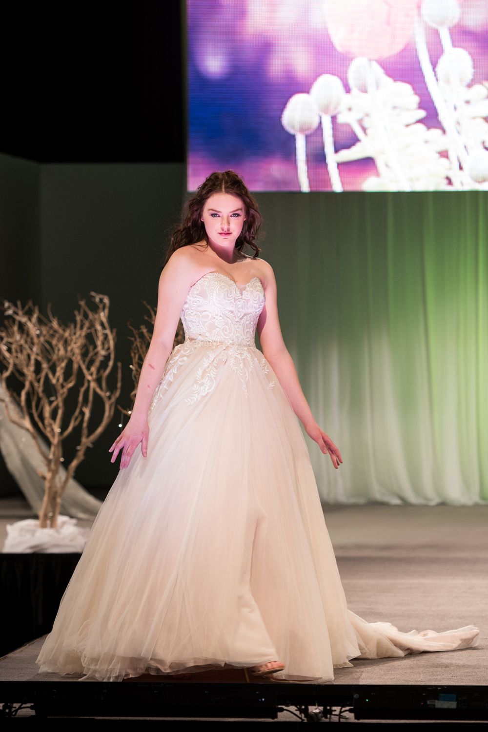 A woman in a wedding dress is walking down a runway.