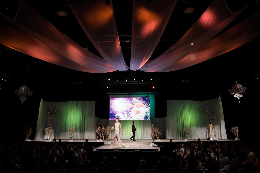 A woman is walking down a runway at a fashion show