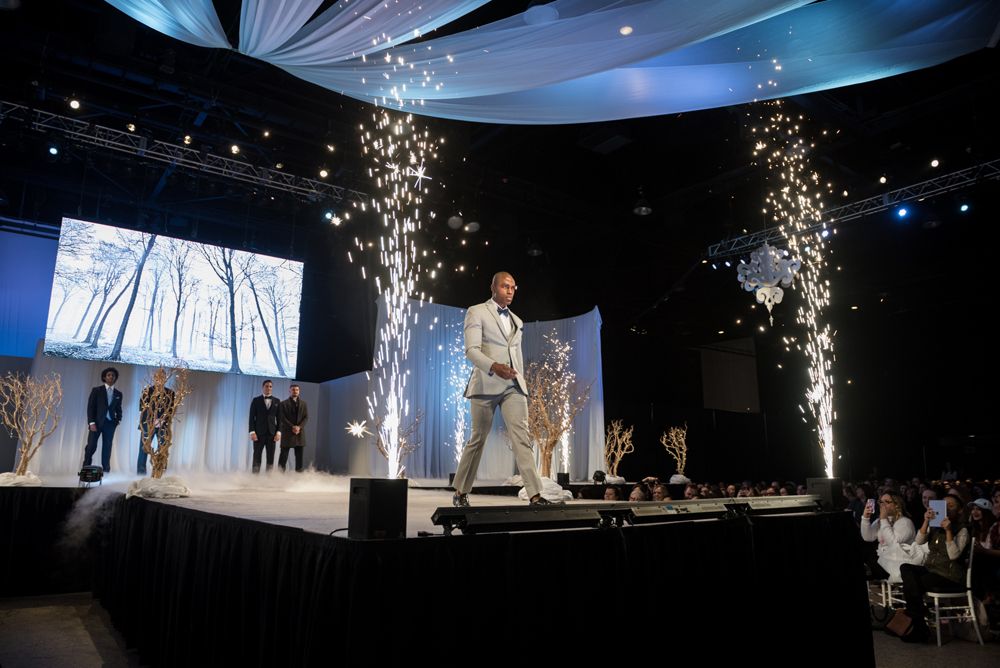 A man is standing on a stage with sparklers coming out of the ceiling.