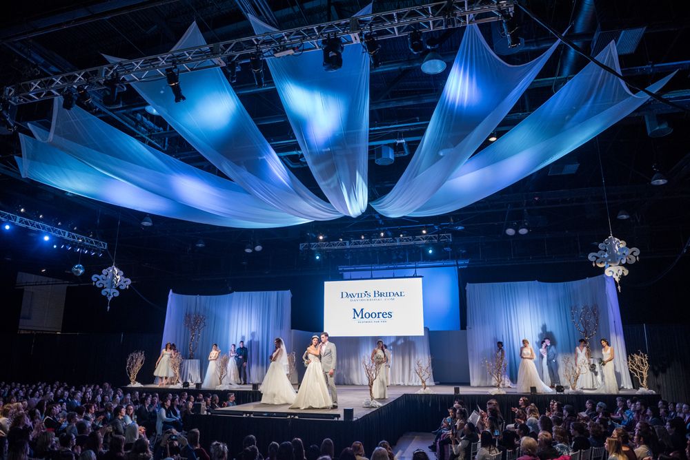 A group of people are standing on a stage at a wedding show.