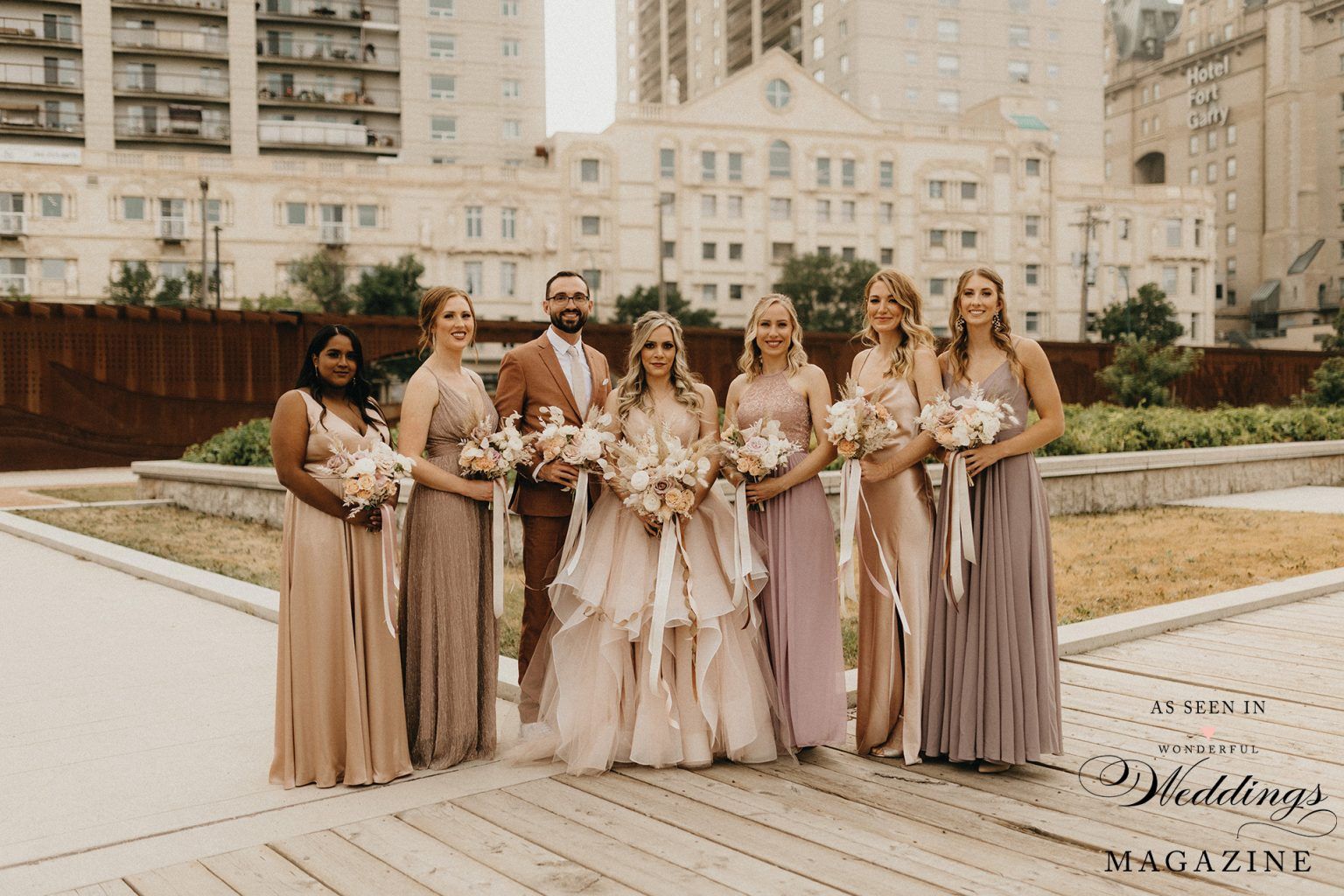 A bride and her bridesmaids are posing for a picture in front of a building.