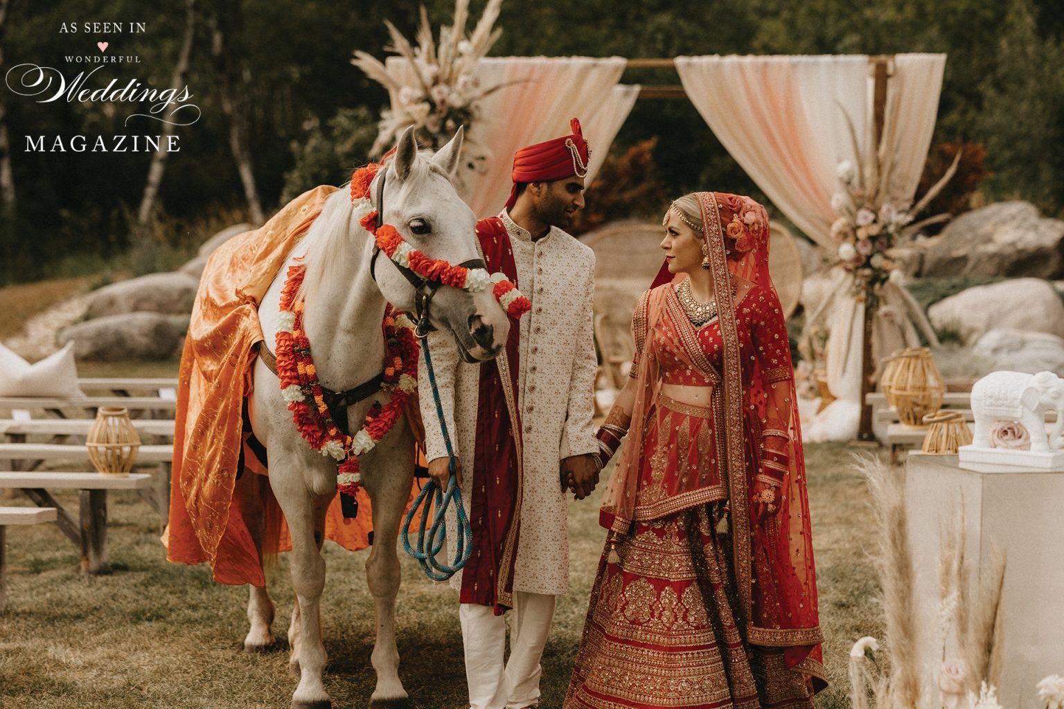 A bride and groom are standing next to a white horse.