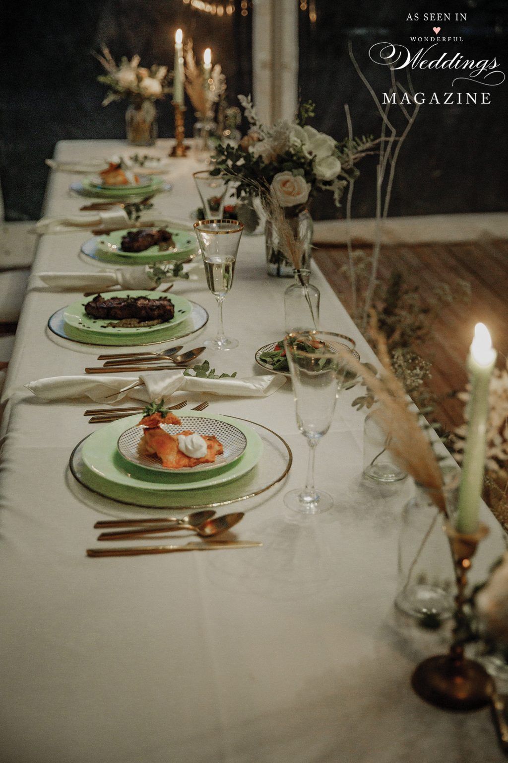 A long table with plates , silverware , candles and flowers on it.