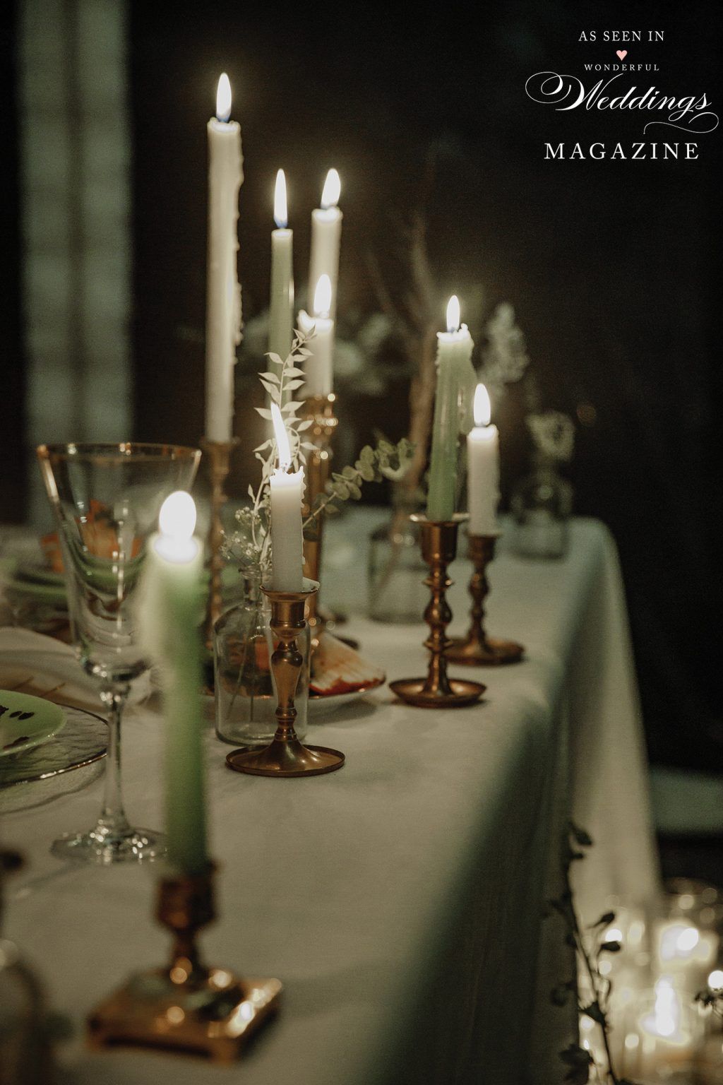 A long table with candles and glasses on it.