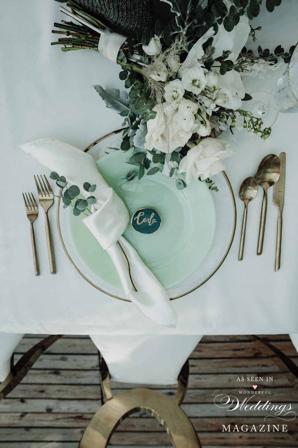 A table with plates , forks , spoons , and flowers on it.