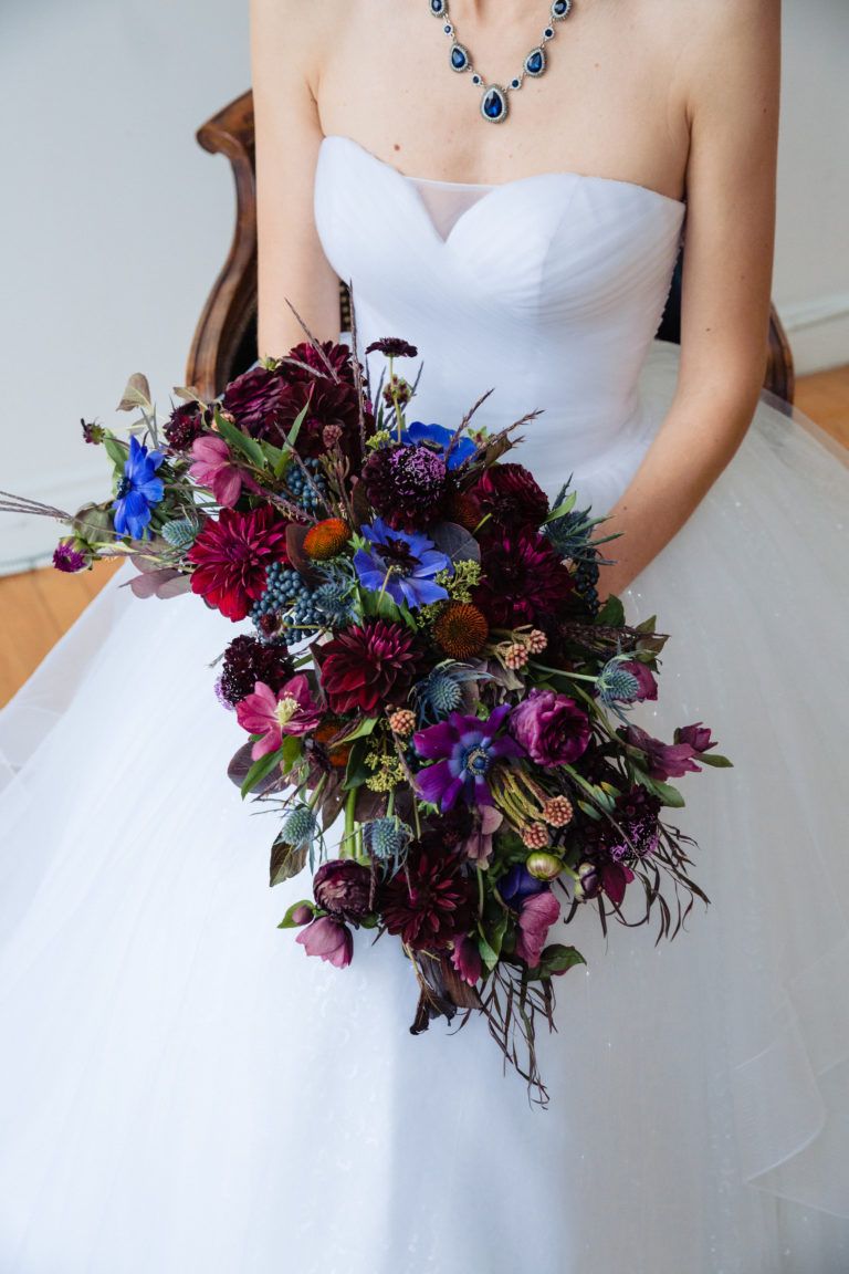 A woman in a white dress is holding a bouquet of flowers.