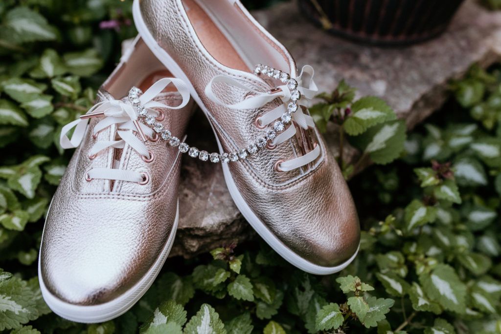 A pair of shoes with a bracelet attached to them are sitting on top of a rock.