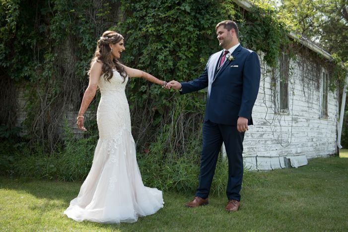 A bride and groom are holding hands in front of a white building.