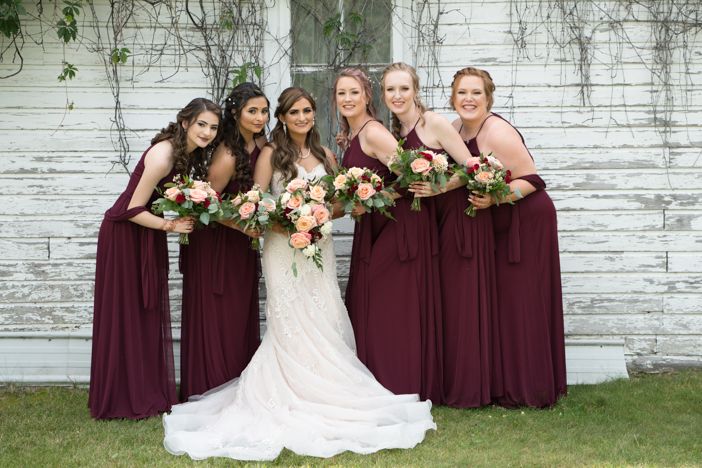 A bride and her bridesmaids are posing for a picture in front of a white building.