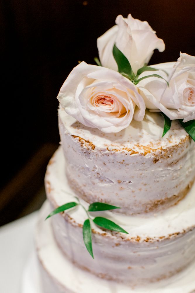 A close up of a wedding cake with roses on top.