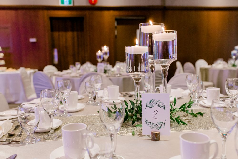 A table set for a wedding reception with candles and a table number.
