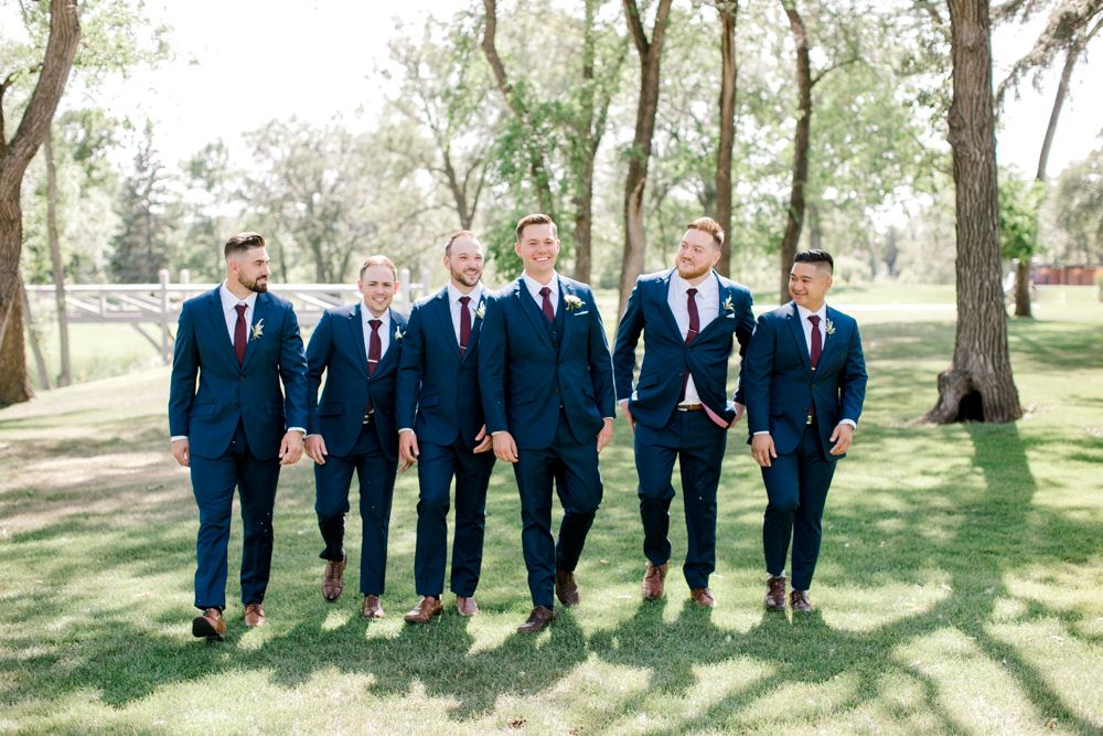 A group of men in suits and ties are walking in a park.