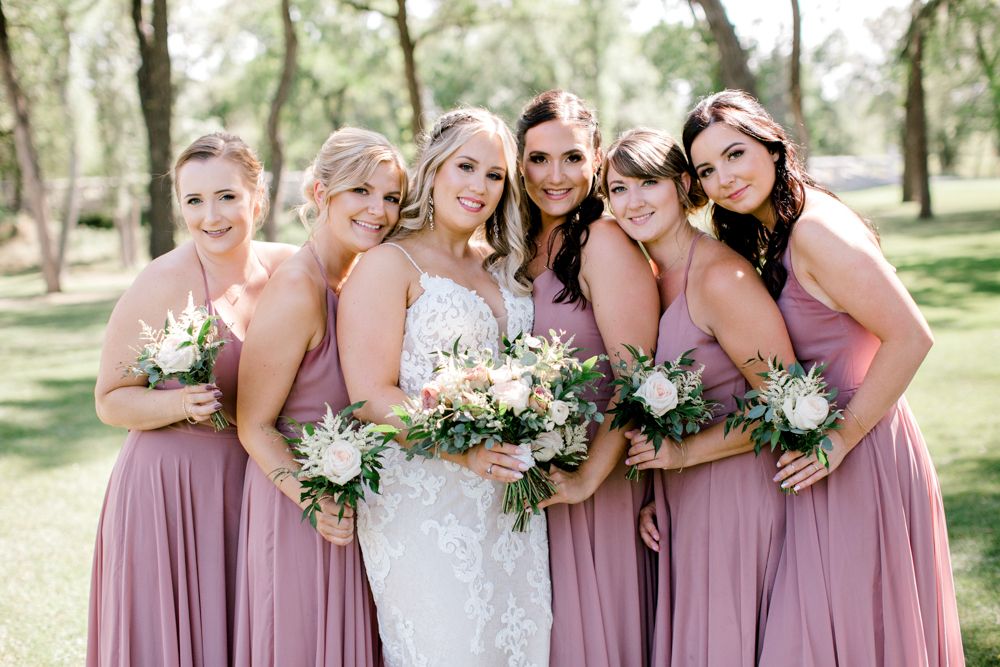 A bride and her bridesmaids are posing for a picture.