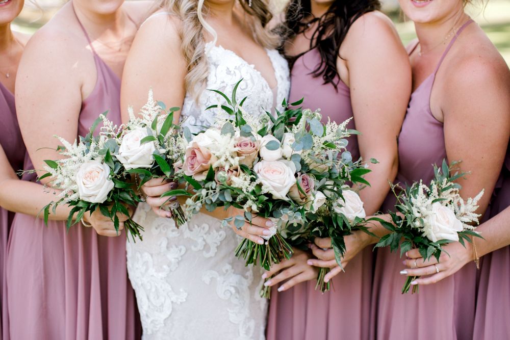 A bride and her bridesmaids are posing for a picture while holding bouquets of flowers.