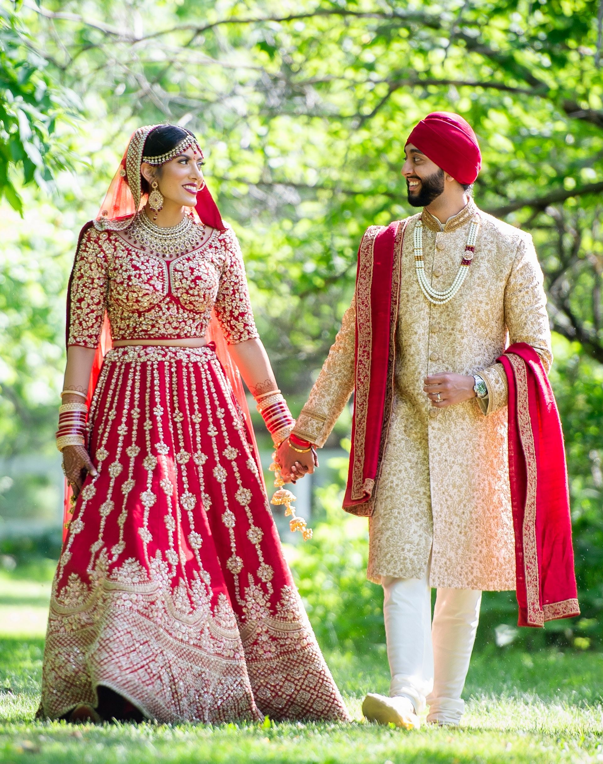 A bride and groom are walking through a park holding hands.