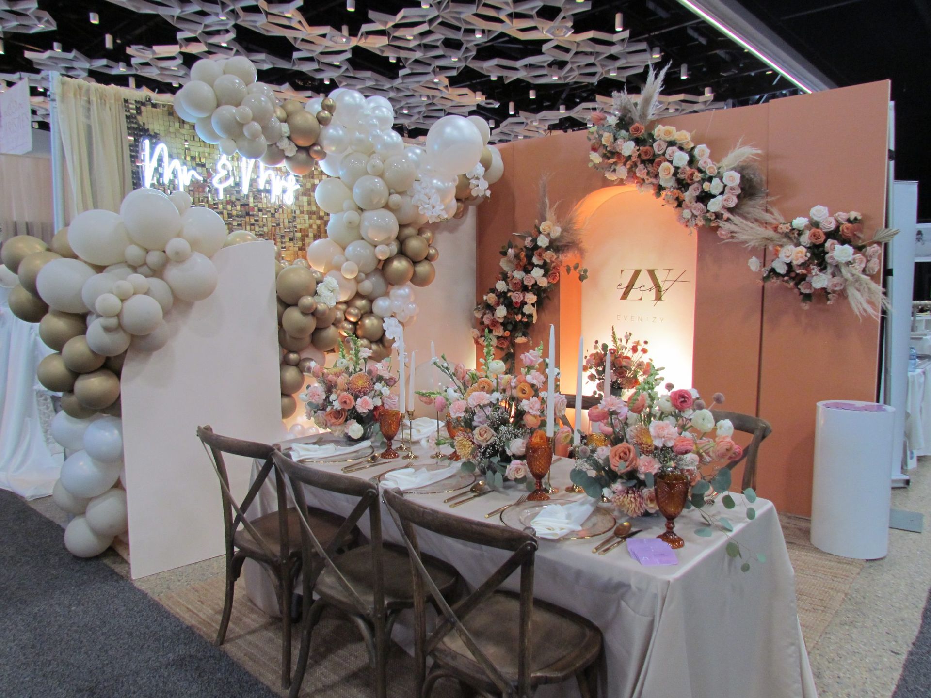 A table and chairs are sitting in front of a wall decorated with balloons and flowers.