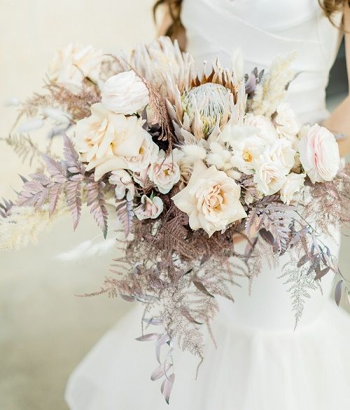 A bride in a white dress is holding a bouquet of flowers.