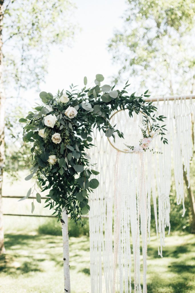 A wedding arch decorated with flowers and a dream catcher.