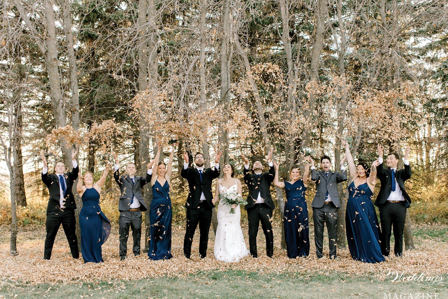 A bride and groom and their wedding party are posing for a picture in the woods.