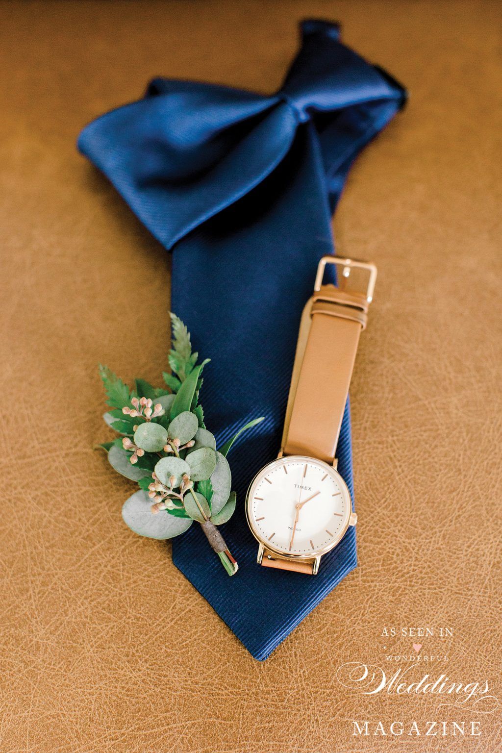 A close up of a watch and a bow tie on a table.