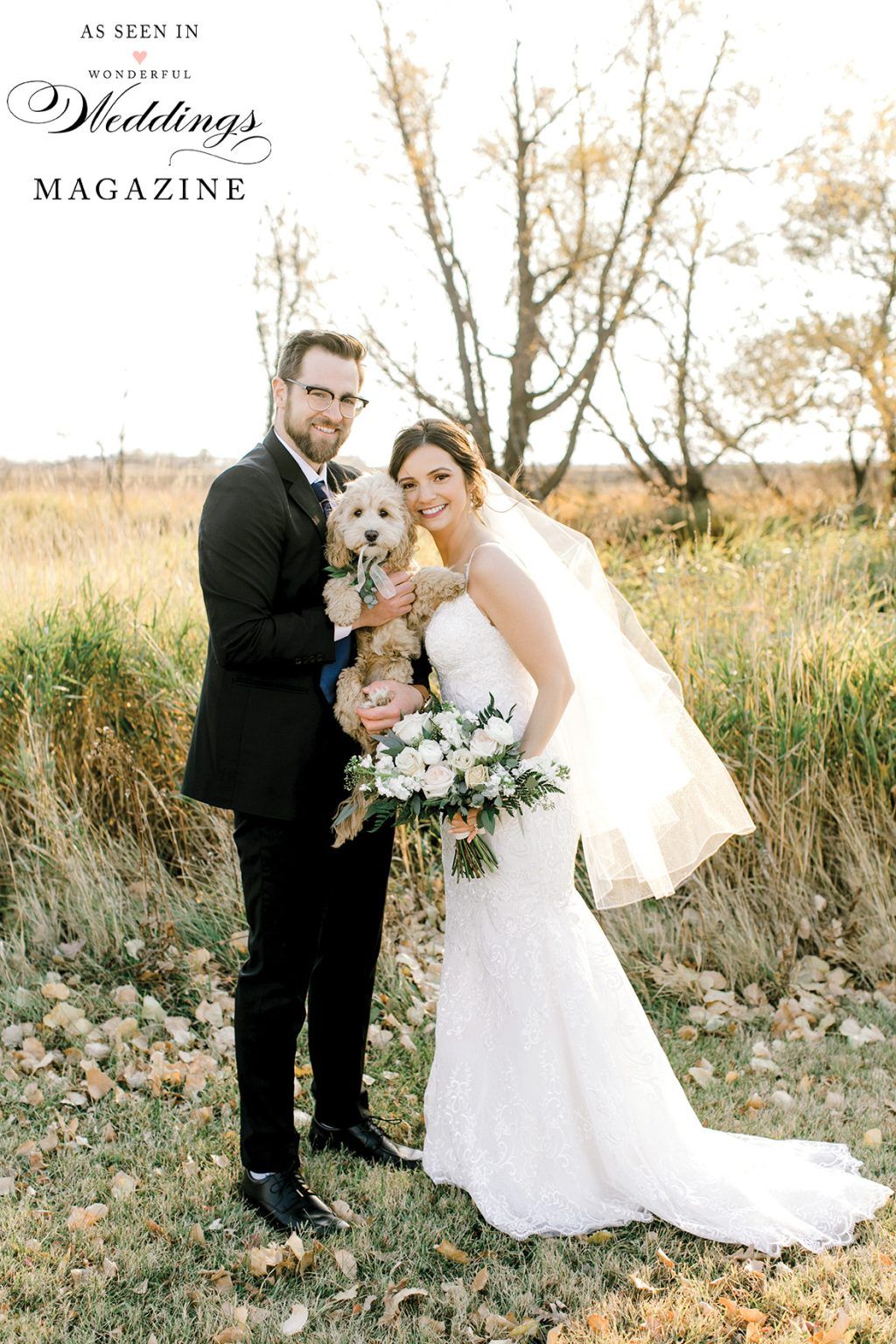 A bride and groom are posing for a picture with their dog.