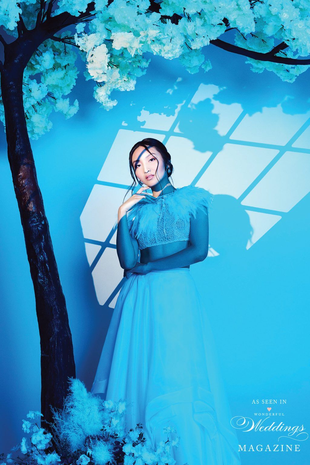 A woman in a blue dress is standing next to a tree.