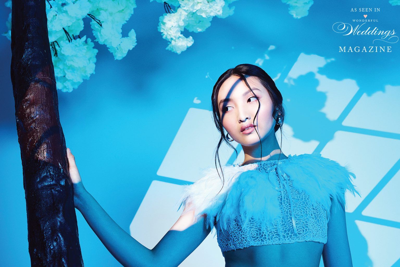 A woman in a blue dress is standing next to a tree