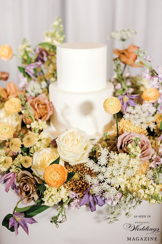 A wedding cake is sitting on top of a table surrounded by flowers.