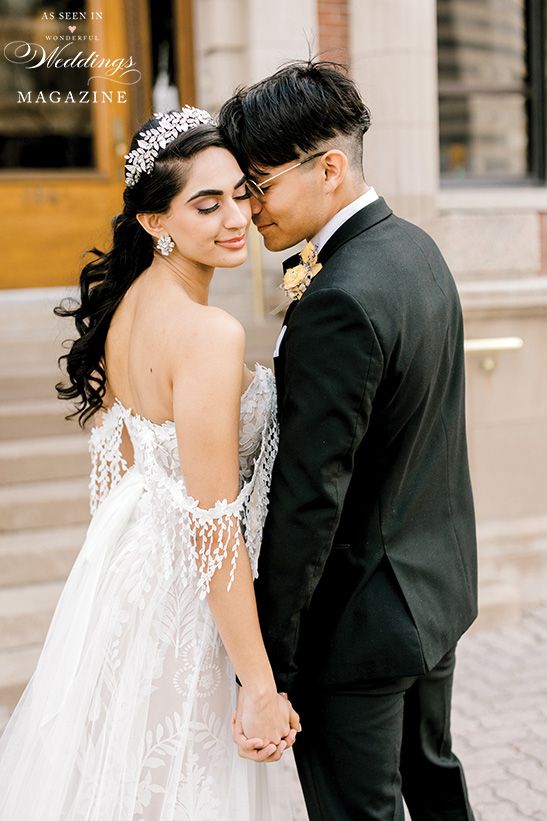 A bride and groom are holding hands and kissing in front of a building.