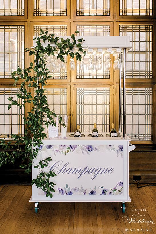 A white cart filled with bottles of champagne and glasses.