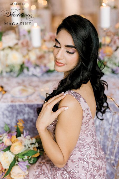 A woman in a pink dress is sitting at a table with flowers.
