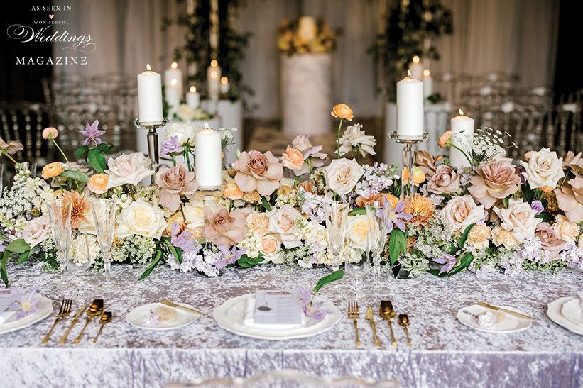 A long table with flowers and candles on it.