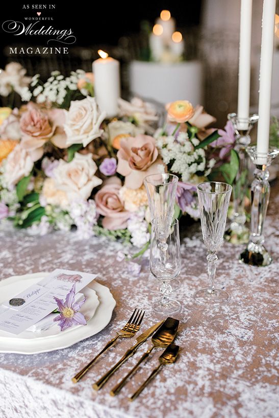A table with plates , silverware , candles and flowers on it.