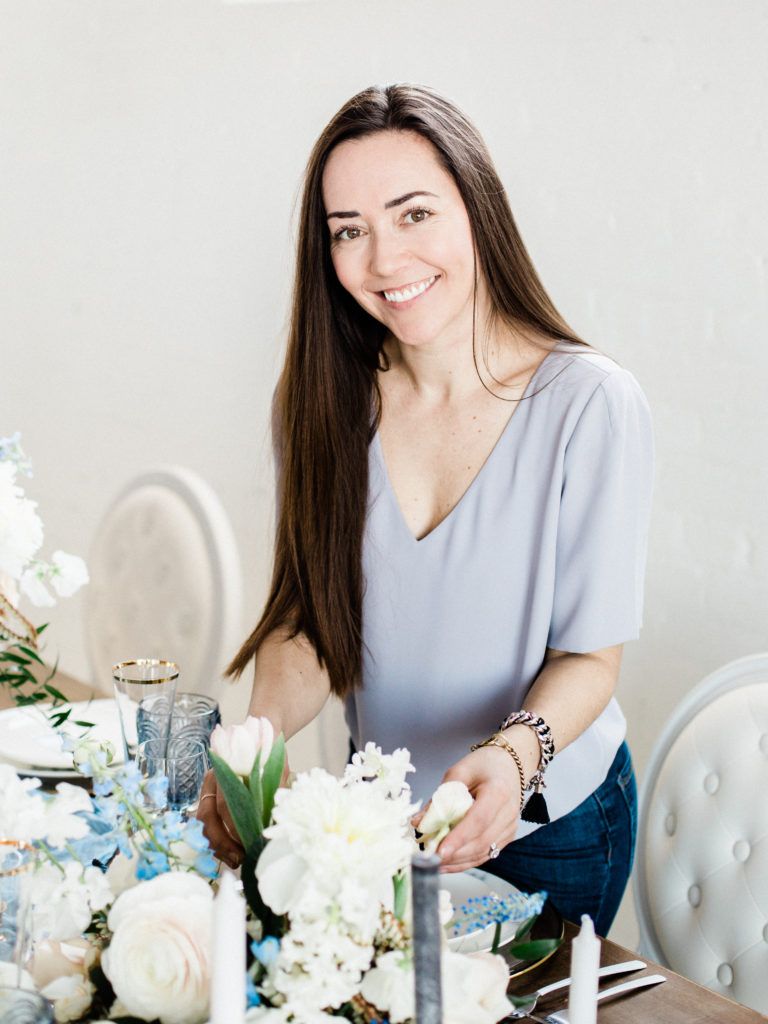 A woman is sitting at a table with flowers and candles.