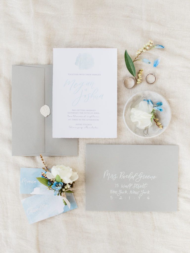 A wedding invitation and envelope are sitting on a bed.
