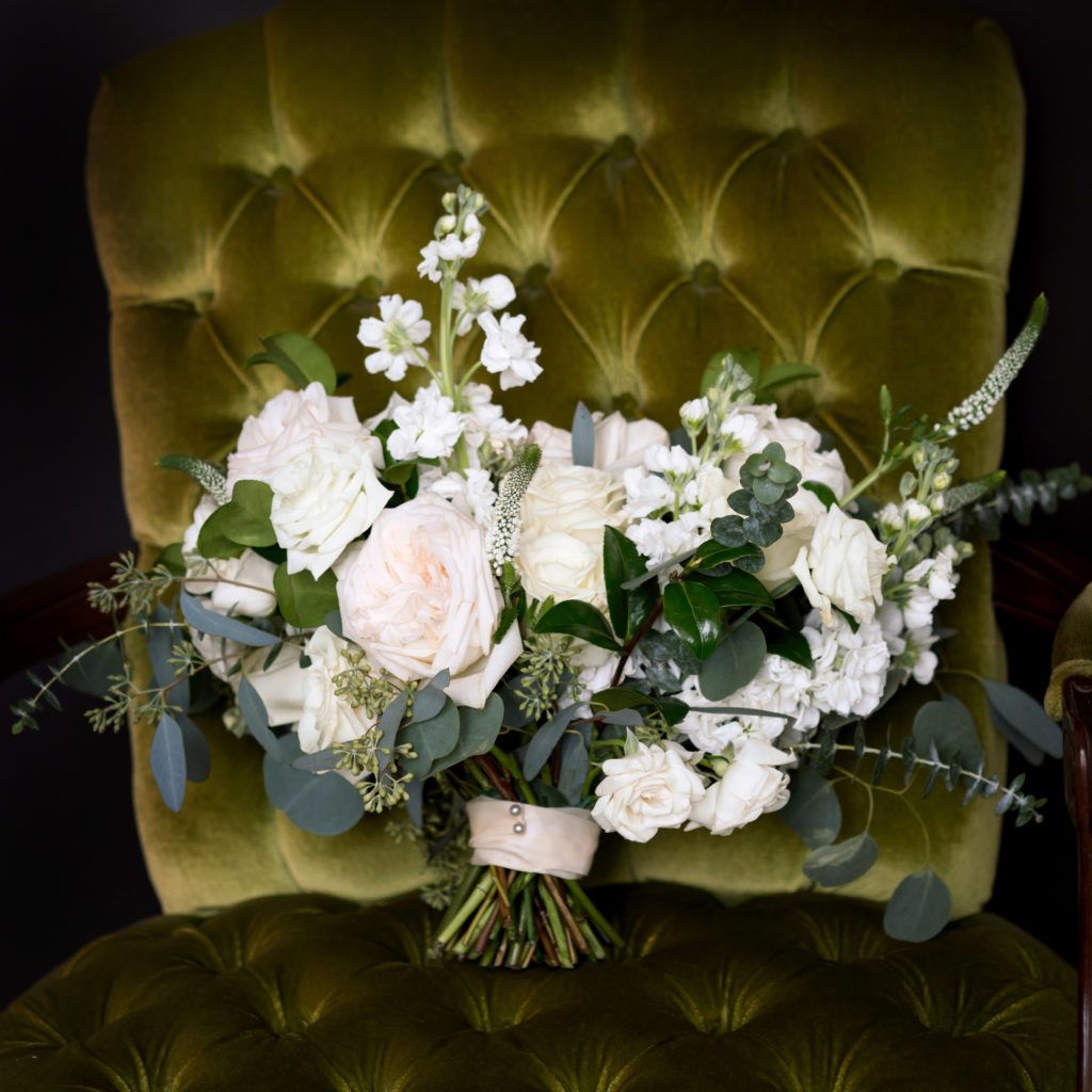 A bouquet of white flowers is sitting on a green chair.
