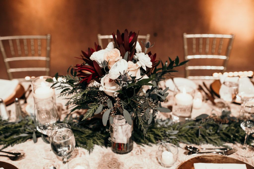 A table set for a wedding reception with a vase of flowers on it.