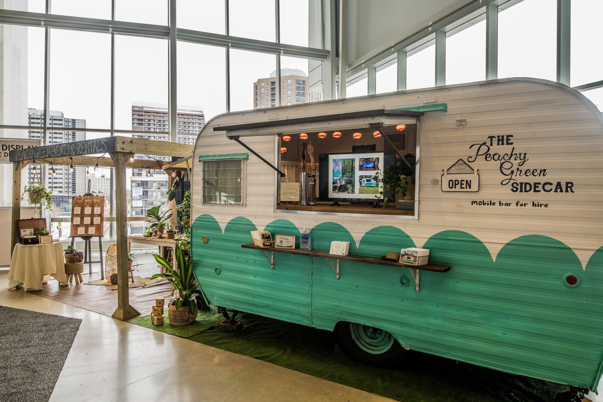 A green and white food truck is parked in a room.