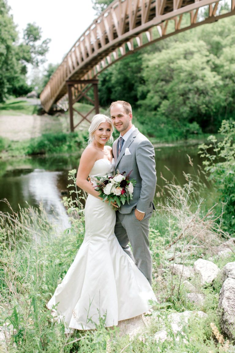 A bride and groom are posing for a picture in front of a bridge.