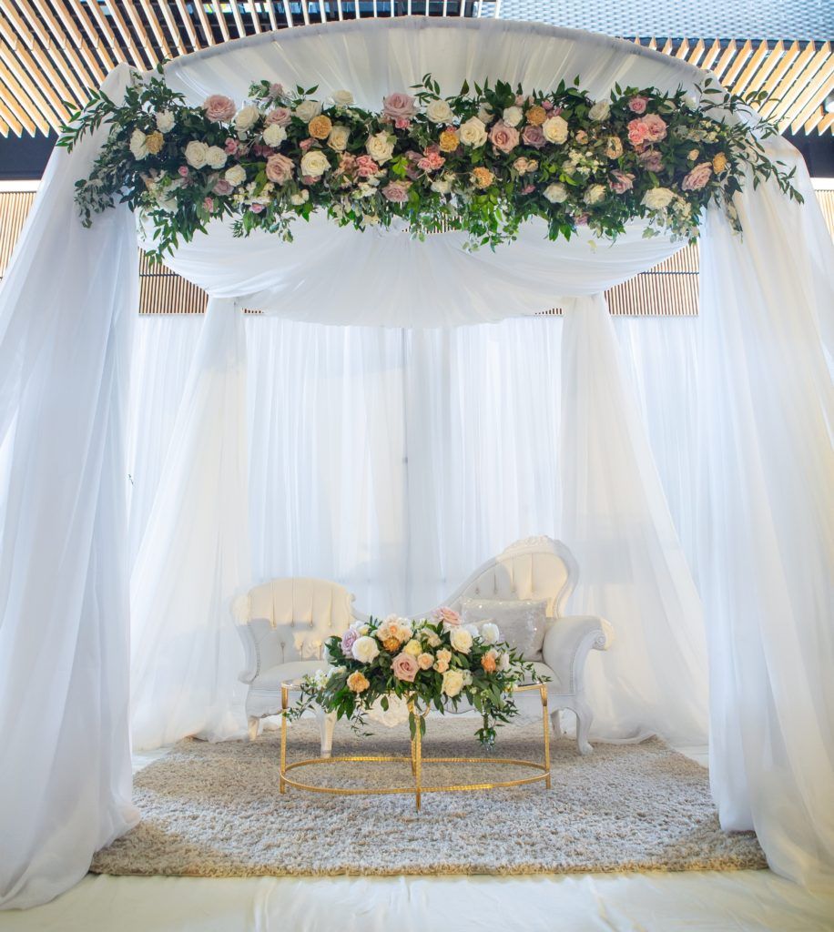 There is a table with flowers on it under a canopy.