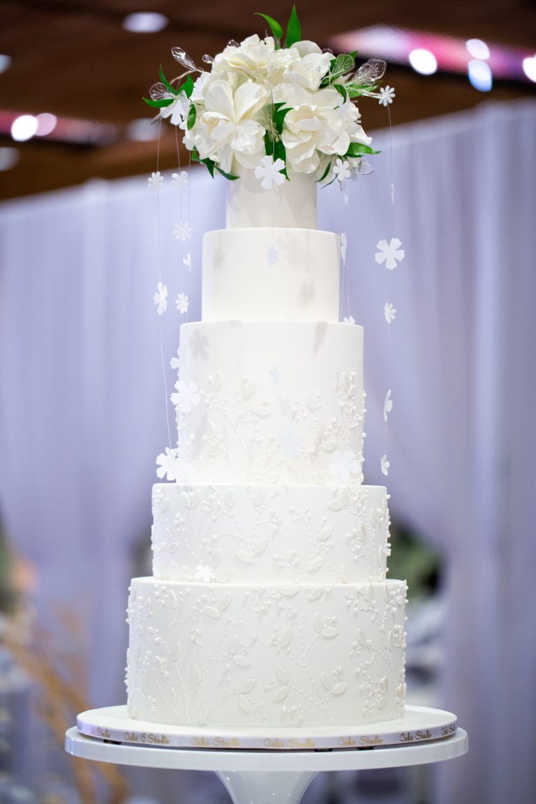 A white wedding cake with flowers on top of it