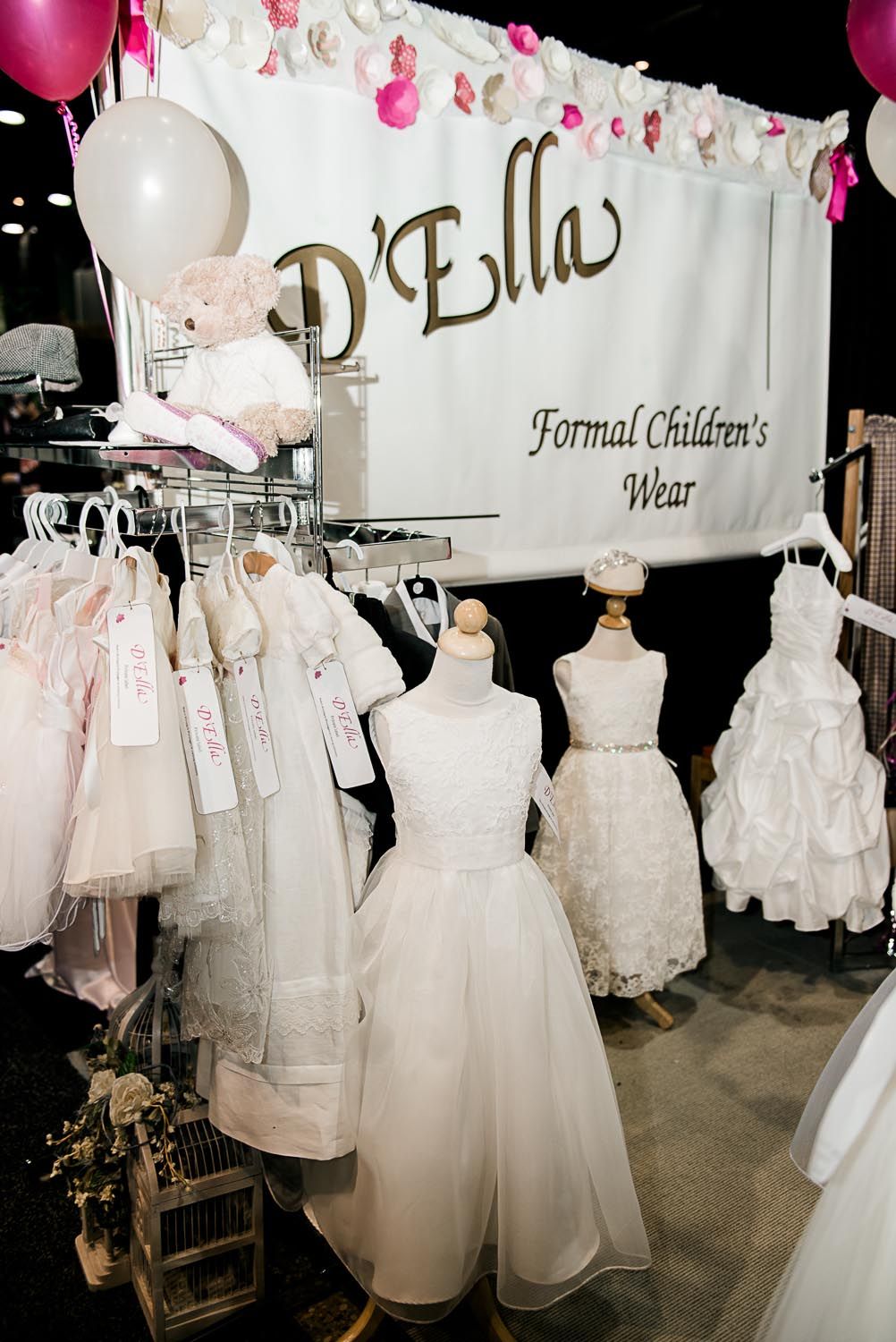 A display of white dresses on mannequins in front of a sign that says d ' ella formal children 's wear