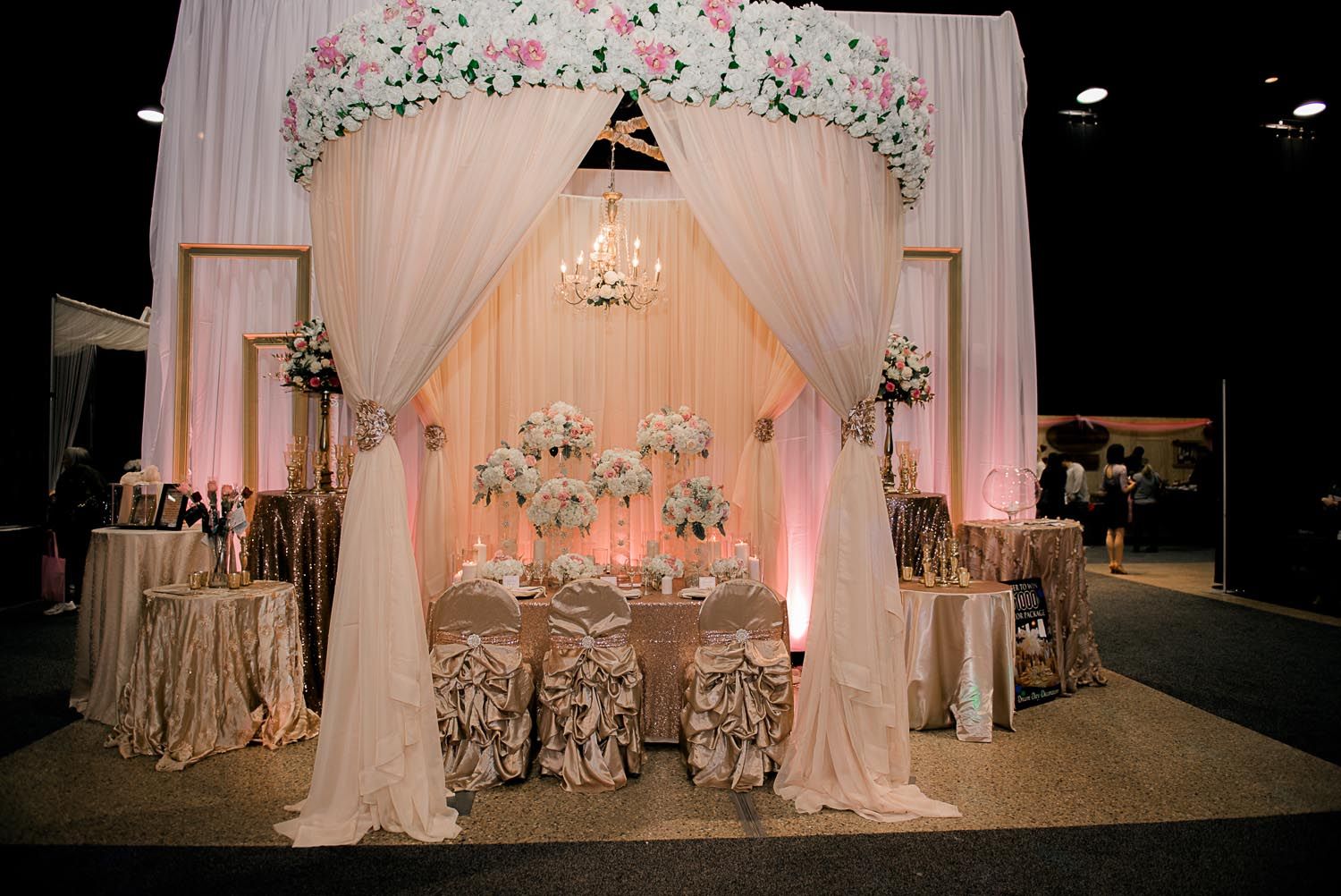 There is a table and chairs under a canopy with flowers on it.