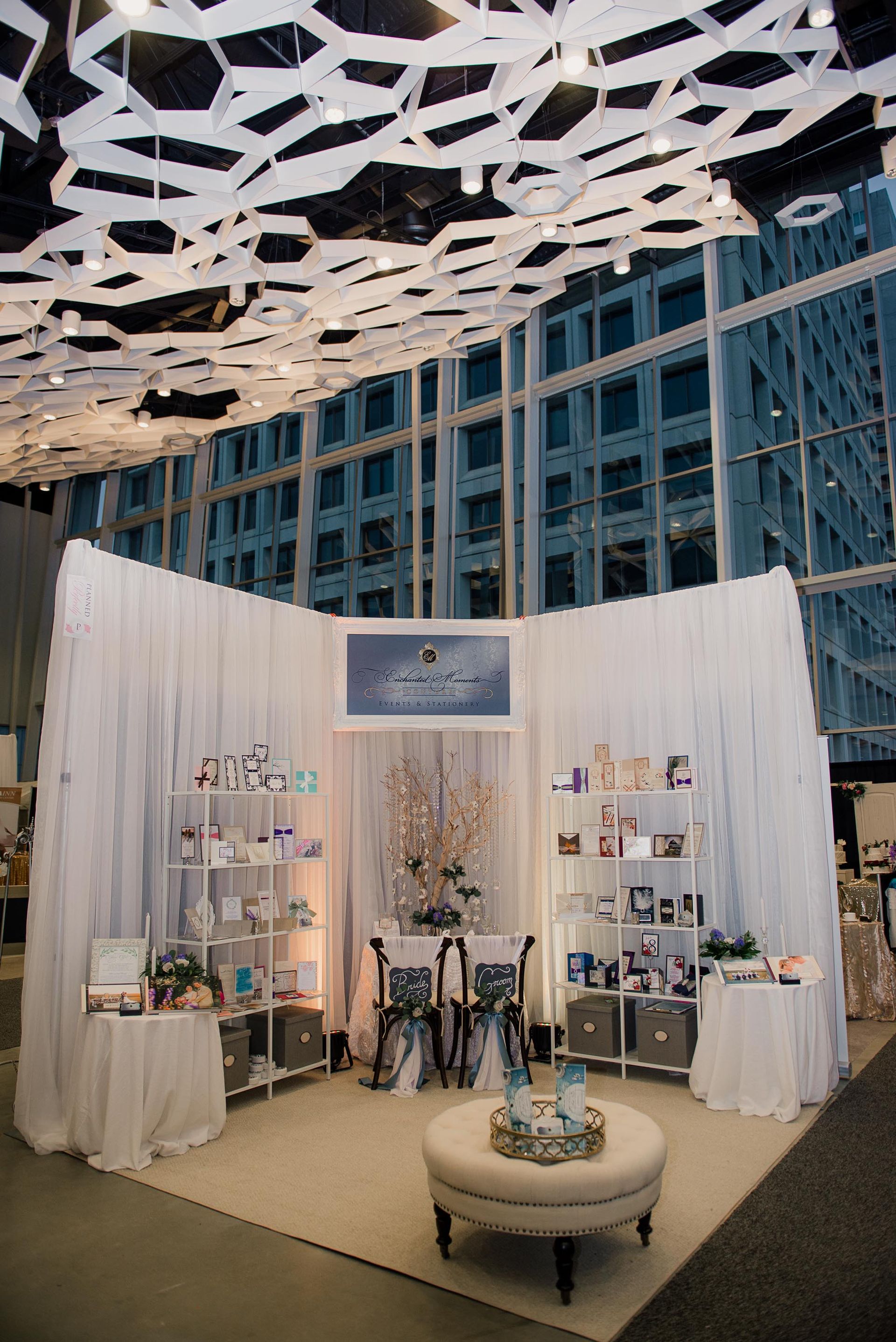 A booth with white curtains and a table in a room with a building in the background.