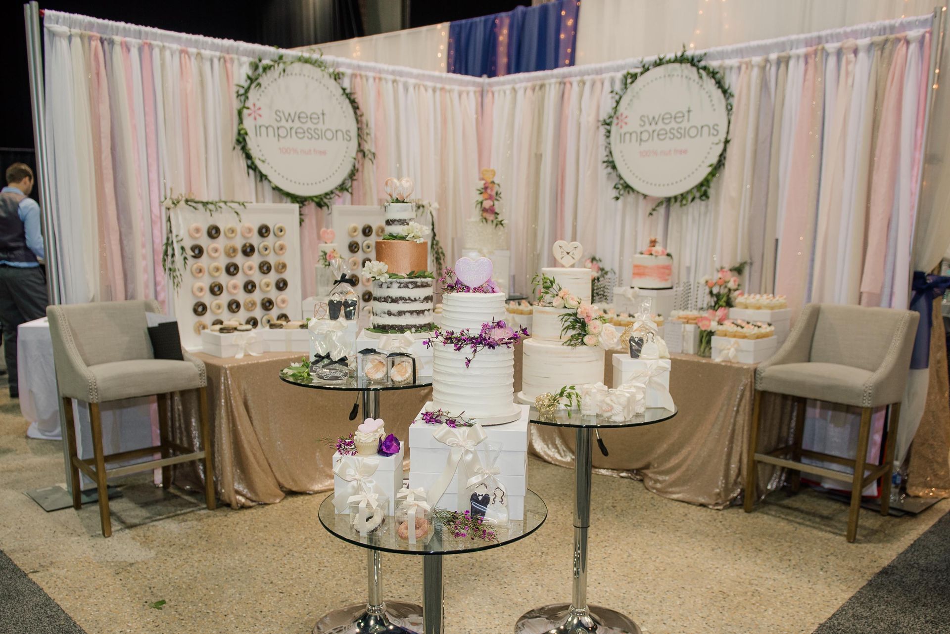 A table with a bunch of cakes on it and chairs in front of it.