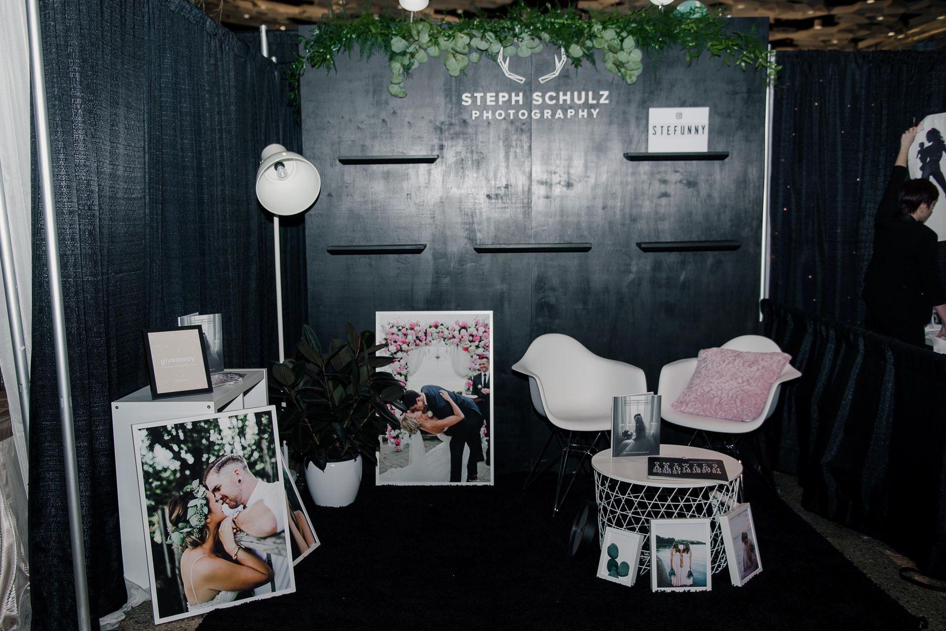 A man is standing in a room with pictures of a bride and groom on display.