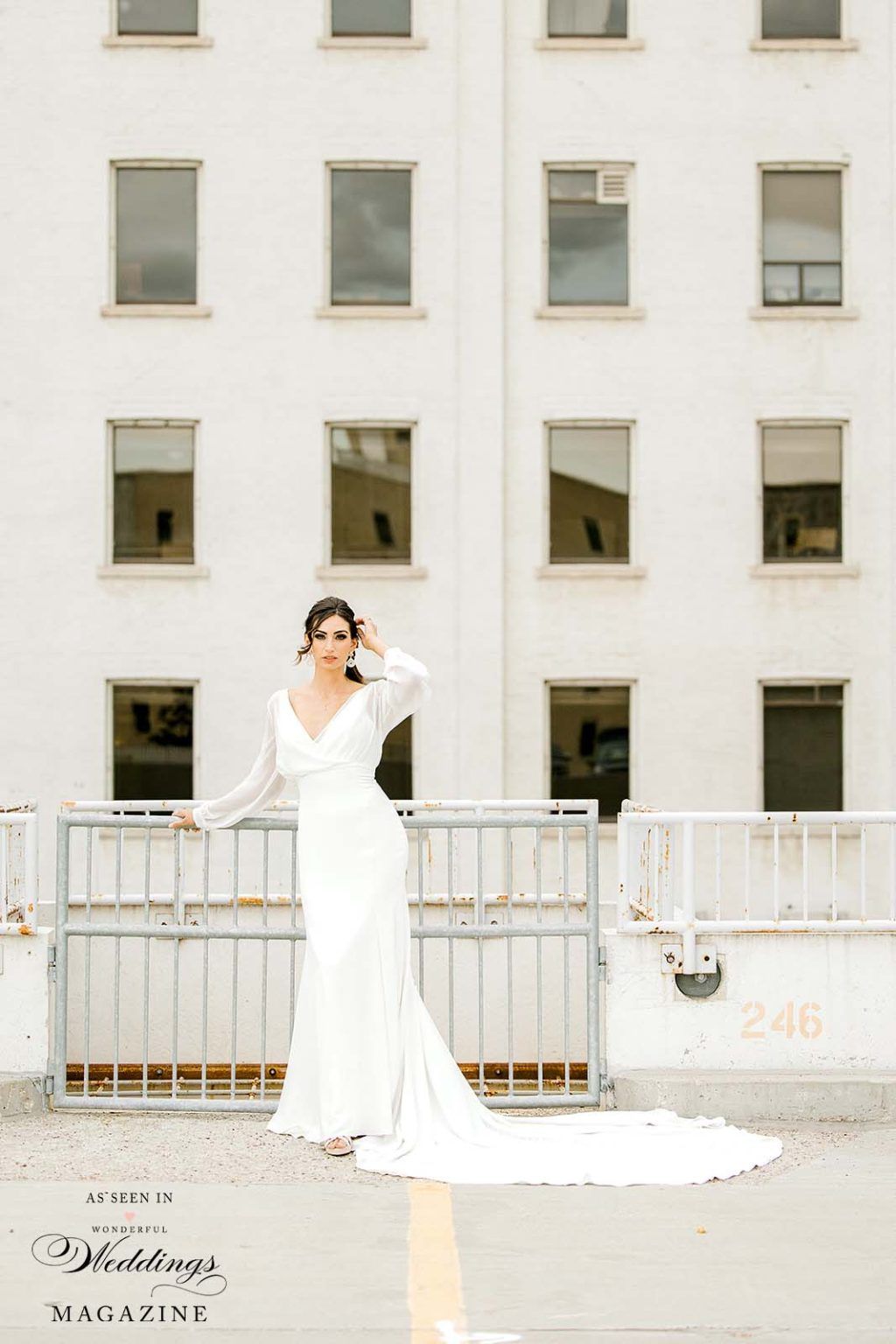A woman in a white dress is standing in front of a white building.