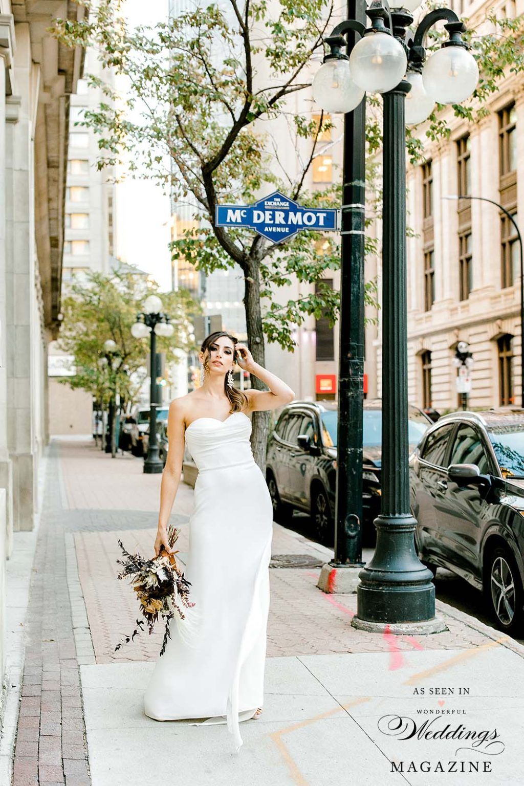 A bride in a white dress is taking a picture of herself on a city street.