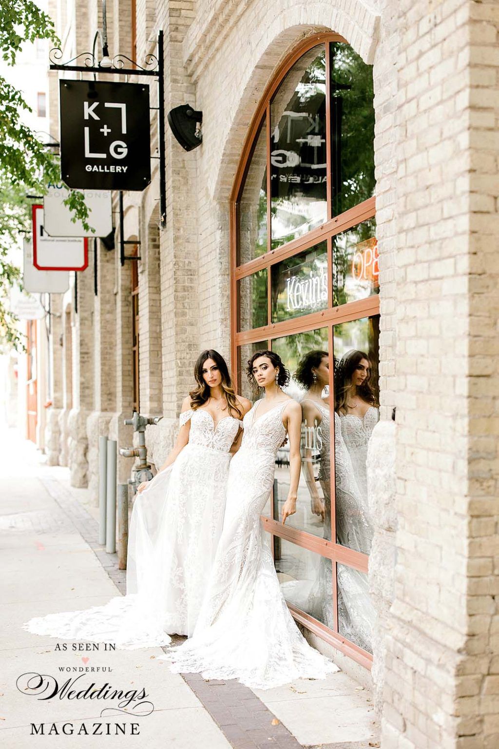 Two women in wedding dresses are standing in front of a building.